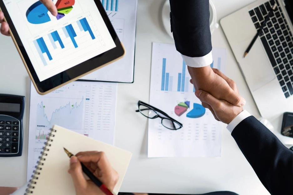 Uśmiechnięty student z laptopem analizujący dane finansowe.